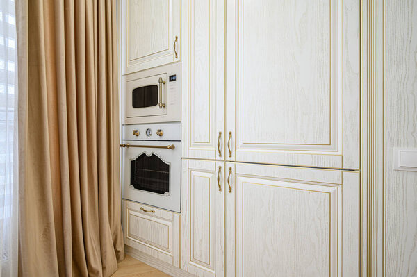 Электрические и микроволновые печи в бежевом интерьере кухни