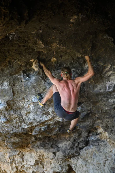 Junger männlicher Kletterer beim Bouldern einer Felswand in einer Höhle — Stockfoto