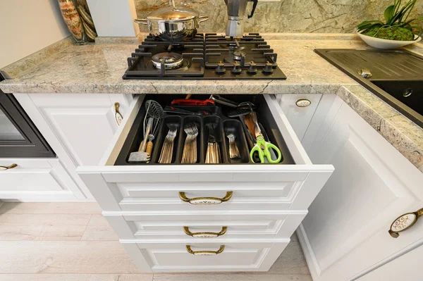 Drawers pulled out at modern classic white kitchen furniture