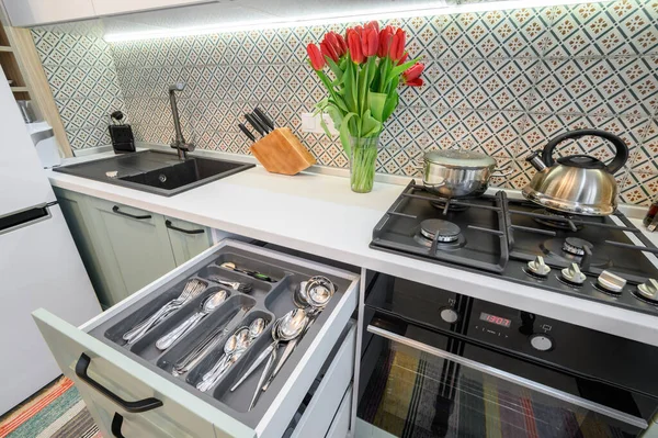 Drawers pulled out in cabinet at luxury teal and white modern kitchen furniture