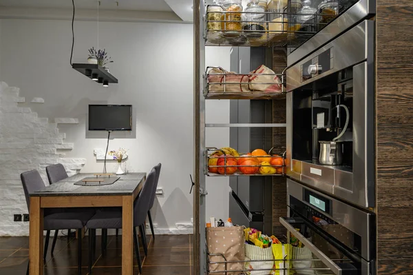 Modern lüks kahverengi mutfak, yemek masası ve dikey çekmece. — Stok fotoğraf