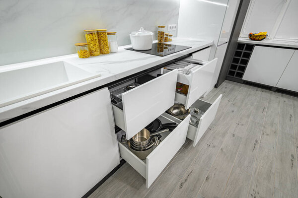 Luxurious white and black modern kitchen interior, drawers pulled out