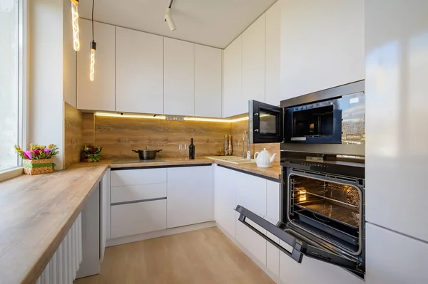 Moderní bílá a béžová dřevěná kuchyň interiér s troubou otevřena — Stock fotografie