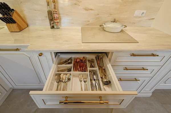 Drawer pulled out in cabinet at luxury beige and gold classic kitchen furniture