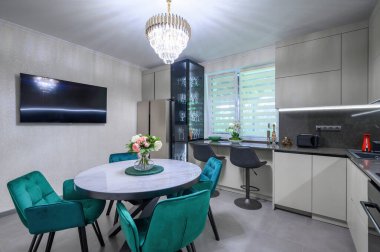 Yemek masası olan büyük, gri bir mutfak.