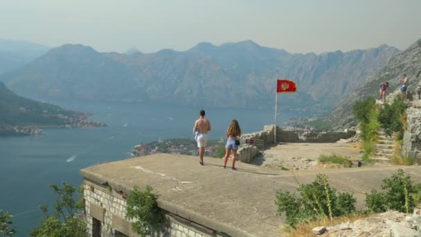 Onbekende toeristen zijn op de top van fort St. John ruïnes, over de stad Kotor en de baai van Kotor, Montenegro — Stockvideo