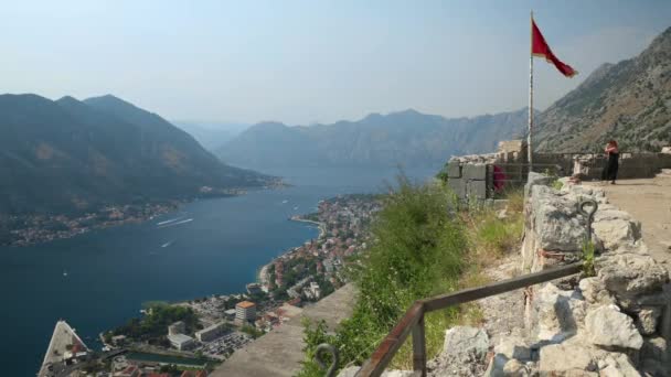 Άγνωστοι τουρίστες βρίσκονται στην κορυφή του φρουρίου του Αγίου Ιωάννη ερείπια, πάνω από την πόλη του Kotor και του κόλπου του Kotor, Μαυροβούνιο — Αρχείο Βίντεο