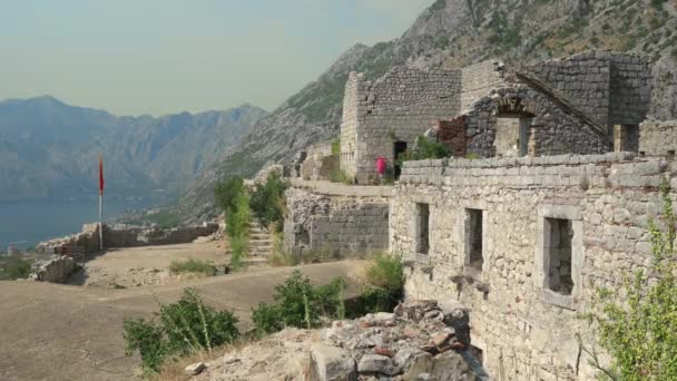 Неизвестные туристы находятся на вершине крепости Сент-Джон руины, над городом Котор и бухтой Котор, Черногория — стоковое видео