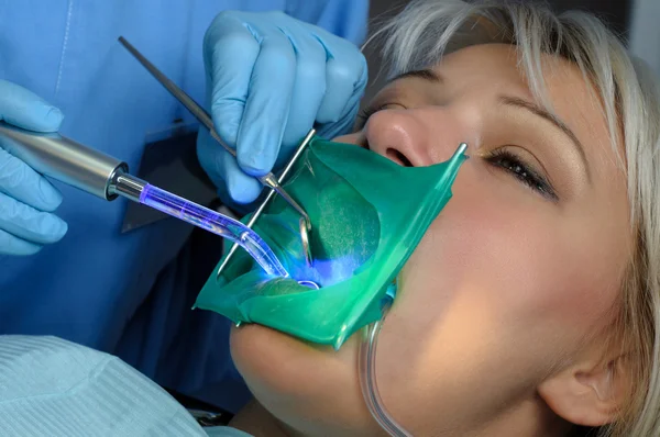 Dentist with patient, using dental curing light — Stock Photo, Image