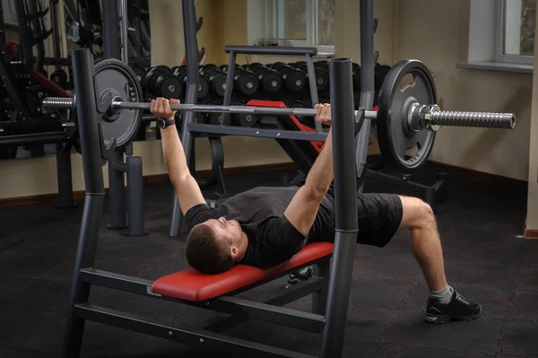 Ung man gör bänk press träning i gym — Stockfoto