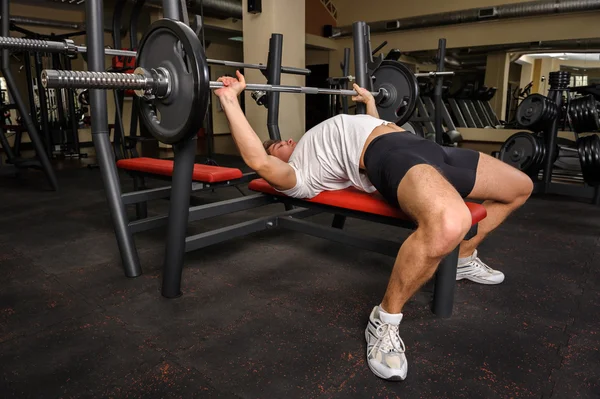 Junger Mann macht Bankdrücken im Fitnessstudio — Stockfoto