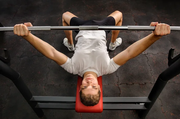 Mladý muž dělá lavice Press cvičení v tělocvičně — Stock fotografie