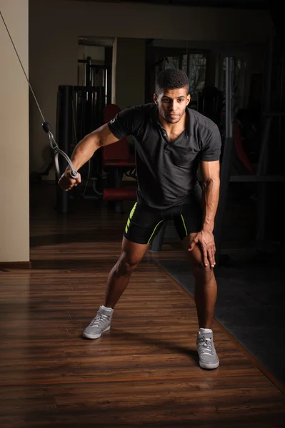 Young man doing one arm standing high cable fly — Stock Photo, Image