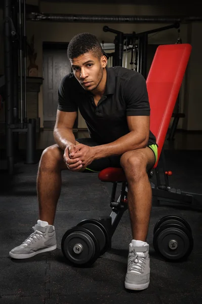 Young man sitting on bench at gym — Stock Photo, Image