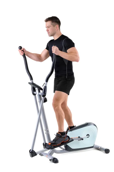 Young man doing exercises on elliptical trainer — Stock Photo, Image