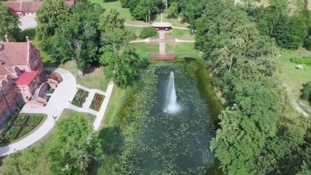 Jaunmoku Ziegelsteinmittelalterliche Burg in der Nähe von Tukums, Lettland am Teich mit Brunnen bei klarem, sonnigem Sommertag von oben. Der Park des Herrenhauses Jaunmokas. Antenne Dron 4k Shot