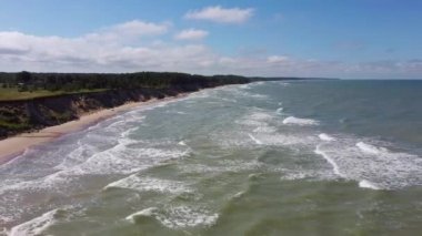 Kıyı şeridi üzerinde uçan Baltık Denizi Uçurumları Pavilosta Letonya 'nın yanındaki Kayalıklar ve Büyük Dalgalı Mağara Uçurumu ve Çakıl Taşları. Aerial Dron Manzarası. Kamera Yana 4K Video Taşıdı