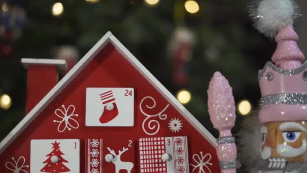 Fa fa adventi naptár előtt egy igazi karácsonyfa díszített diótörő katona játékok. Tündérfény egy karácsonyfán homályos háttérrel. Dolly Slider 4K lövés. Rögzítés
