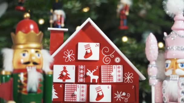 本物のクリスマスツリーの前に木製の木のアドベントカレンダー飾りくるみ割り人形兵士のおもちゃ 背景がブルーのクリスマスツリー上の妖精の光 Dolly Slider Shot ラックフォーカス — ストック動画
