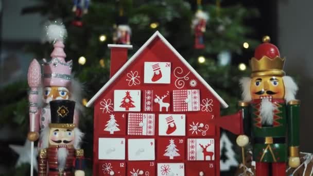 本物のクリスマスツリーの前に木製の木のアドベントカレンダー飾りくるみ割り人形兵士のおもちゃ 背景がブルーのクリスマスツリー上の妖精の光 Dolly Slider Shot ラックフォーカス — ストック動画