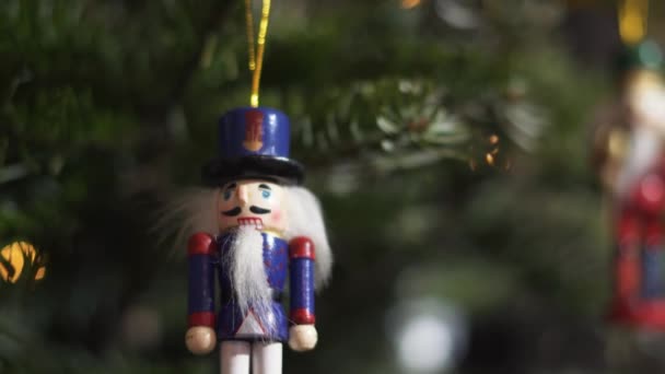 Díszítés Toy Diótörő karácsonyfán. 4K Dolly Slider Shot. Diótörő katona egy karácsonyfán homályos háttérrel. Gyönyörű díszített karácsonyfa, a diótörő játék, tündér fények.