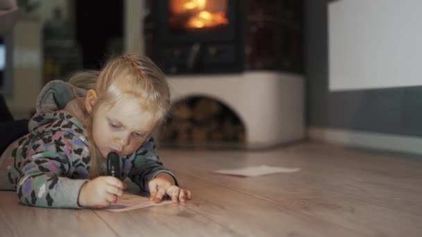 Mała Dziewczynka Leżąca Podłodze Pokoju Pisząca Rysująca Przytulna Atmosfera Płonącym — Wideo stockowe