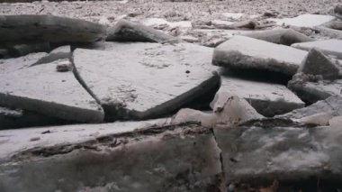 Letonya, Ogre nehrinde devasa buz yığınları sürükleniyor. Snowy Mart 'ta Stedicam shot günü. İlkbaharda nehirde trafik sıkışık. Büyük bir hareketli buz kütlesi. Arkaplanda Köprü