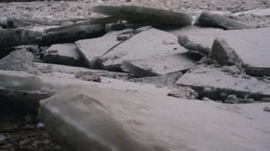 Letonya, Ogre nehrinde devasa buz yığınları sürükleniyor. Snowy Mart 'ta Stedicam shot günü. İlkbaharda nehirde trafik sıkışık. Büyük bir hareketli buz kütlesi. Arkaplanda Köprü