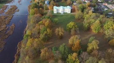 Letonya Mezotne şehrinin sonbahar havası. Mezotne Sarayı ve Park. Arka plandaki Lielupe Nehri. Renkli Sonbahar Manzarası. Yeşil, Kırmızı, Turuncu ve Sarı Yapraklar.