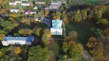 Letonya Mezotne şehrinin sonbahar havası. Mezotne Sarayı ve Park. Arka plandaki Lielupe Nehri. Renkli Sonbahar Manzarası. Yeşil, Kırmızı, Turuncu ve Sarı Yapraklar.