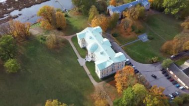 Letonya Mezotne şehrinin sonbahar havası. Mezotne Sarayı ve Park. Arka plandaki Lielupe Nehri. Renkli Sonbahar Manzarası. Yeşil, Kırmızı, Turuncu ve Sarı Yapraklar.