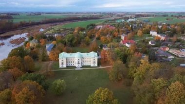 Letonya Mezotne şehrinin sonbahar havası. Mezotne Sarayı ve Park. Arka plandaki Lielupe Nehri. Renkli Sonbahar Manzarası. Yeşil, Kırmızı, Turuncu ve Sarı Yapraklar.