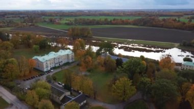 Letonya Mezotne şehrinin sonbahar havası. Mezotne Sarayı ve Park. Arka plandaki Lielupe Nehri. Renkli Sonbahar Manzarası. Yeşil, Kırmızı, Turuncu ve Sarı Yapraklar.