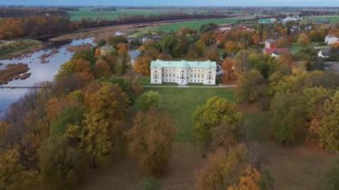 Letonya Mezotne şehrinin sonbahar havası. Mezotne Sarayı ve Park. Arka plandaki Lielupe Nehri. Renkli Sonbahar Manzarası. Yeşil, Kırmızı, Turuncu ve Sarı Yapraklar.