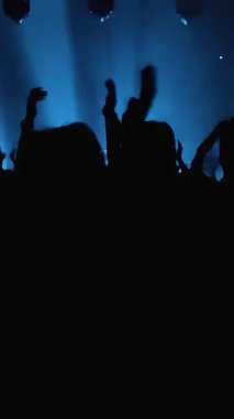 Tanınmayan Hayranlar Bir Konser veya Festival Partisinde Dans Etmek ve Ellerini Kaldırmak. Seyircilerin Siluetleri Parlak Sahne Işıklarının Önündeki Konserin tadını çıkarıyor.