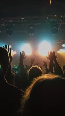Tanınmayan Hayranlar Bir Konser veya Festival Partisinde Dans Etmek ve Ellerini Kaldırmak. Seyircilerin Siluetleri Parlak Sahne Işıklarının Önündeki Konserin tadını çıkarıyor.