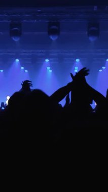 Tanınmayan Hayranlar Bir Konser veya Festival Partisinde Dans Etmek ve Ellerini Kaldırmak. Seyircilerin Siluetleri Parlak Sahne Işıklarının Önündeki Konserin tadını çıkarıyor.