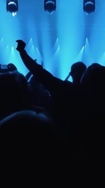 Tanınmayan Hayranlar Bir Konser veya Festival Partisinde Dans Etmek ve Ellerini Kaldırmak. Seyircilerin Siluetleri Parlak Sahne Işıklarının Önündeki Konserin tadını çıkarıyor.