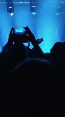 Tanınmayan Hayranlar Bir Konser veya Festival Partisinde Dans Etmek ve Ellerini Kaldırmak. Seyircilerin Siluetleri Parlak Sahne Işıklarının Önündeki Konserin tadını çıkarıyor.