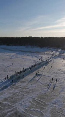 Buz kaplı eski ahşap iskelede donmuş Baltık Denizi 'nin ve güneşli bir kış gününde buzda yürüyen insanların Letonya' nın 4K seyahat sahnesinin keyfini çıkardığı video.