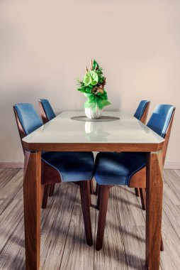 Oturma odasındaki cam yemek masasında vazoya konmuş yeşil Anthurium andraeanum çiçeği. Ev dekorunda hava temizleyici bitkiler