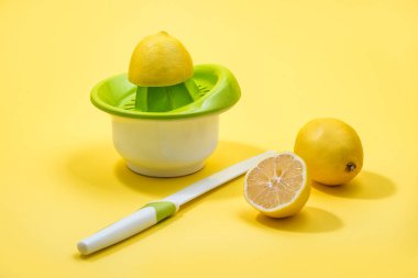 Renkli sarı arkaplan üzerinde elle tutulan bir Citrus sıkacağı ile sıkılmış Lemon