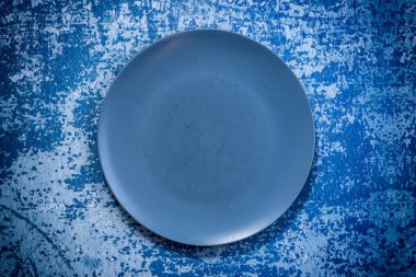 Mavi rustik arka planda büyük bir lacivert plaka. Çizikli kullanılmış tabak. Seçici odaklanma. Yukarıdan ateş edildi