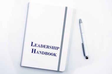 White Leadership Handbook or manual with White pen on white table surface - personnel management policy, explains business goals, results, defines Leadership practices clipart