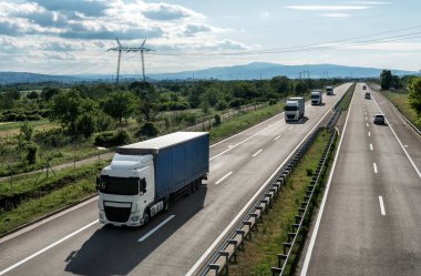 Gün batımında güzel bir gökyüzüne sahip araç ve kamyonetlerle dolu bir konvoy.