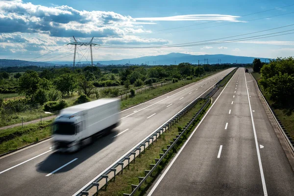 Transportation Truck in high speed on a highway through rural landscape. Fast blurred motion drive on the freeway. Freight scene on the motorway