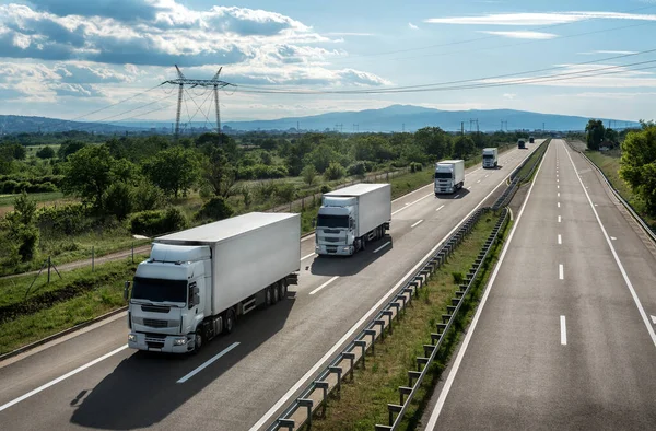 Transportation trucks passing by on a country highway under a beautiful sky. Business Transportation And Trucking Industry.