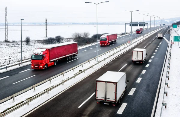 Highway transportation with a convoy of Lorry trucks passing trucks in a snowy winter landscape