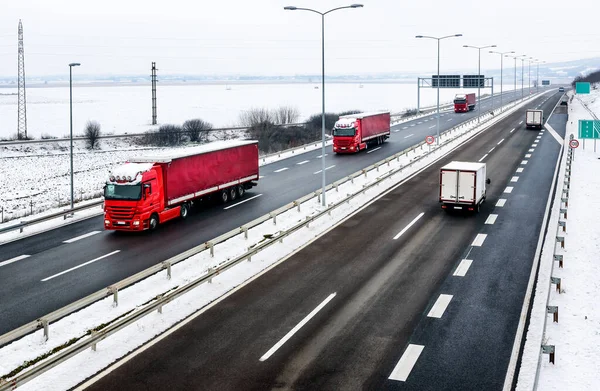 Highway transportation with a convoy of Lorry trucks passing trucks in a snowy winter landscape