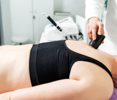 Lazer terapisi. Hastanın sırtını ve omzunu tedavi eden fizyoterapist. Kadın sabırlı